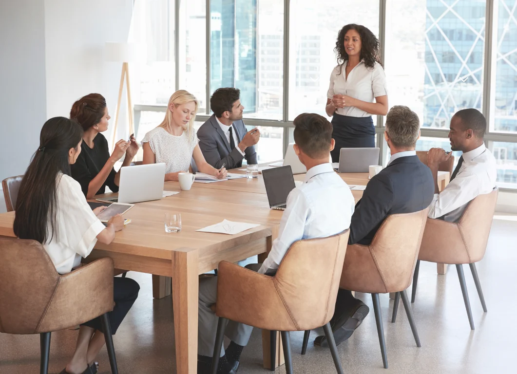 Group of diverse professionals collaborating around a desk in a modern office setting. Group of diverse professionals collaborating around a desk in a modern office setting.
